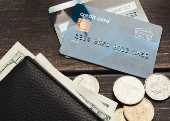 Dollar banknotes in wallet with coins and credit card on wooden table. Commerce, domestic finance concept, copy space