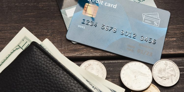 Dollar banknotes in wallet with coins and credit card on wooden table. Commerce, domestic finance concept, copy space