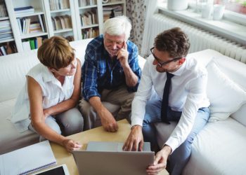 Senior couple planning their investments with financial advisor in living room