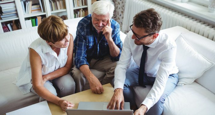 Senior couple planning their investments with financial advisor in living room