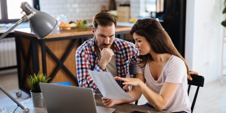 Frustrated couple checking bills at home using laptop